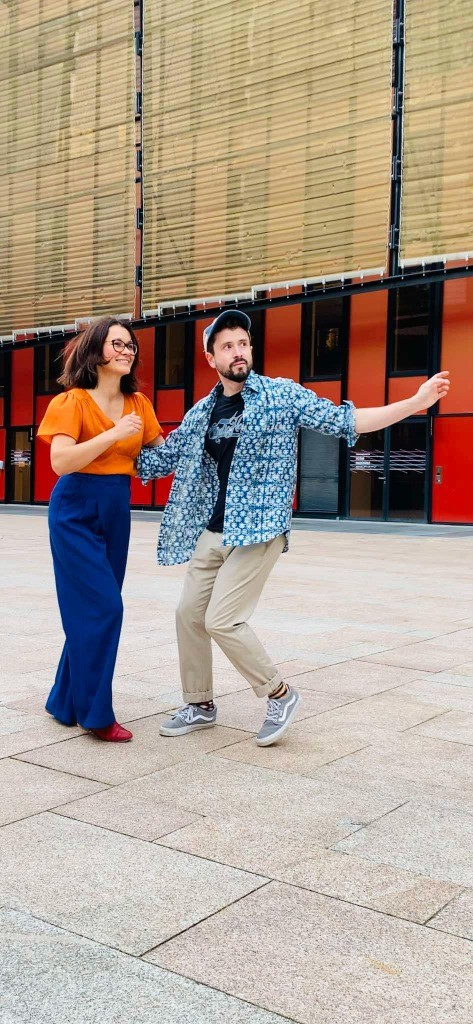 Couple de danseurs de lindy hop devant un bâtiment moderne